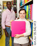 Portrait of happy woman demonstrating pink folder in stationary department of store. Стоковое фото, фотограф Яков Филимонов / Фотобанк Лори
