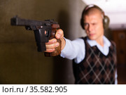 Hand of shooter squeezing pistol grip and pressing trigger at firing range. Стоковое фото, фотограф Яков Филимонов / Фотобанк Лори