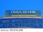 Ощадбанк (Сбербанк). Вывеска на крыше здания на фоне голубого неба. Украина (2021 год). Редакционное фото, фотограф FMRU / Фотобанк Лори