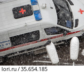 Вид сверху на машину скорой помощи, принадлежащей частной  медицинской клинике, во время снегопада (2021 год). Редакционное фото, фотограф Наталья Николаева / Фотобанк Лори
