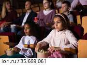 Preteen girl with mulatta mate watching movie in cinema. Стоковое фото, фотограф Яков Филимонов / Фотобанк Лори