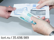 Russia, Samara, February 2021: men's hands transfer money to pay a fine for violation of traffic rules. Text in Russian: 1000 rubles, receive letters in electronic form, identification of the state registration plate, save yours, time is not refundable. Редакционное фото, фотограф Акиньшин Владимир / Фотобанк Лори