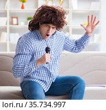 Funny man singing songs in karaoke at home. Стоковое фото, фотограф Elnur / Фотобанк Лори
