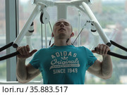 Молодой мужчина выполняет жим не тренажёре (2021 год). Редакционное фото, фотограф Дмитрий Неумоин / Фотобанк Лори
