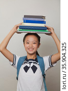 Girl smiling and holding bunch of notebooks and laptop on her head, Studio. Стоковое фото, агентство Ingram Publishing / Фотобанк Лори