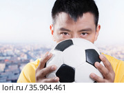 Footballer holding ball against his face. Стоковое фото, агентство Ingram Publishing / Фотобанк Лори