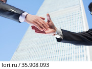 Close-up of two business people shaking hands by the World Trade Center in Beijing, China. Стоковое фото, агентство Ingram Publishing / Фотобанк Лори