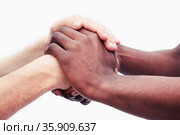 Two young men clasping each others hands, close-up, studio shot. Стоковое фото, агентство Ingram Publishing / Фотобанк Лори