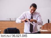 Young male employee stapling paper in the office. Стоковое фото, фотограф Elnur / Фотобанк Лори