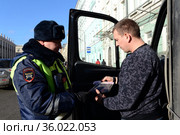 Инспектор дорожно-патрульной службы полиции проверяет документы водителя остановленного автомобиля (2017 год). Редакционное фото, фотограф Free Wind / Фотобанк Лори