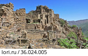 Ruins of ancient Gamsutl village with abandoned building stone walls on mountain slope cliff against blue sky on sunny day in Dagestan Russia (2021 год). Стоковое видео, видеограф Алексей Кузнецов / Фотобанк Лори