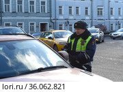 Инспектор дорожно-патрульной службы полиции разговаривает с водителем остановленного автомобиля в центре Москвы (2017 год). Редакционное фото, фотограф Free Wind / Фотобанк Лори