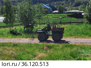 Man with children rides a makeshift swamp buggy through the village in Perm Krai, Russia (2021 год). Редакционное фото, фотограф Евгений Харитонов / Фотобанк Лори