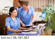 Two focused physicians working with case histories on laptop. Стоковое фото, фотограф Яков Филимонов / Фотобанк Лори