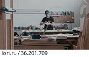 Man in a carpentry workshop looking at the grinded wooden piece. Стоковое видео, видеограф Константин Шишкин / Фотобанк Лори