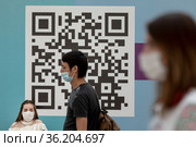 Люди ждут очереди в центре вакцинации на фоне QR-кода в городе Москве, Россия (2021 год). Редакционное фото, фотограф Николай Винокуров / Фотобанк Лори