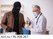 Masked man burglar bribing old doctor for getting vaccine. Стоковое фото, фотограф Elnur / Фотобанк Лори