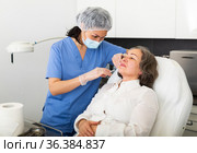 Young cosmetologist doctor in a protective mask makes an elderly woman patient a injecting an injection into the face. Стоковое фото, фотограф Яков Филимонов / Фотобанк Лори
