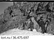Двое военных стоят на снегу у скалы с ружьями в руках, мужчины с оружием в военной униформе, село Уэлен, Чукотка, 1970 год. Редакционное фото, фотограф Варфоломей Тетерин / Фотобанк Лори