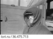 Молодой мужчина стоит в тёплой куртке под открытым небом, научный сотрудник полярной метеостанции рядом с бульдозером, село Уэлен, Чукотка, 1970 год. Редакционное фото, фотограф Варфоломей Тетерин / Фотобанк Лори