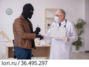 Masked man burglar bribing old doctor for getting vaccine. Стоковое фото, фотограф Elnur / Фотобанк Лори