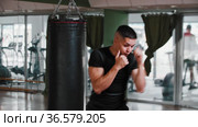 Young man with short hair performing shadow boxing in the gym. Стоковое видео, видеограф Константин Шишкин / Фотобанк Лори