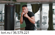 Young man in sports clothes performing shadow boxing in the gym - looking in the camera. Стоковое видео, видеограф Константин Шишкин / Фотобанк Лори