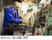 Confident gunsmith lubricates and cleans barrel of rifled shotgun. Стоковое фото, фотограф Яков Филимонов / Фотобанк Лори