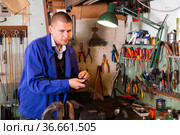 Confident gunsmith lubricates and cleans barrel of rifled shotgun. Стоковое фото, фотограф Яков Филимонов / Фотобанк Лори