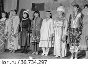 Люди в традиционной одежде разных народов стоят на одной сцене, девушки выступают в нарядах разных культур. Женщины в русских, якутских, татарских одеждах, Якутия. Редакционное фото, фотограф Варфоломей Тетерин / Фотобанк Лори