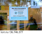Информационный плакат с надписью "Все сотрудники вакцинированы" на входной двери продовольственного супермаркета. Эпидемия коронавируса COVID-19 в России. Калининград (2021 год). Редакционное фото, фотограф Ирина Борсученко / Фотобанк Лори