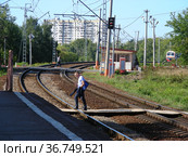 Люди переходят железнодорожные пути по деревянному настилу рядом с железнодорожной платформой станции "Водники" Савёловского направления Московской железной дороги. Город Долгопрудный. Московская область (2011 год). Редакционное фото, фотограф lana1501 / Фотобанк Лори
