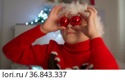 Child in a Santa hat holds red balloons, boy is playing with Christmas tree toys. Waiting for new year. Positive pre-holiday mood. Decoration of Christmas tree with red balls. Dabble with balls. Стоковое видео, видеограф Ирина Ткачук / Фотобанк Лори