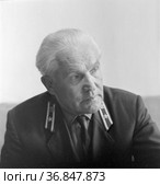 Фотопортрет сосредоточенного мужчины, офицер внимательно смотрит вперед, седовласый человек с погонами позирует сидя в помещении, Якутия, 1967 год. Редакционное фото, фотограф Варфоломей Тетерин / Фотобанк Лори