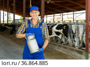Smiling farmer standing in cowshed at dairy farm with milk churn. Стоковое фото, фотограф Яков Филимонов / Фотобанк Лори