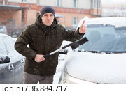 An adult man portrait with snow brush in hand gesturing thumb up while clearing his car in winter season. Стоковое фото, фотограф Кекяляйнен Андрей / Фотобанк Лори