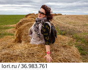 Женщина на фоне стогов сена, уходящих за горизонт. Деревня Моховое. Куркинский район. Тульская область (2021 год). Стоковое фото, фотограф Сергей Афанасьев / Фотобанк Лори