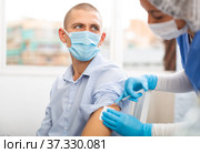 Doctor in a protective mask injects a vaccine to a man with syringe. Стоковое фото, фотограф Яков Филимонов / Фотобанк Лори