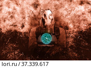 A shot of a man dressed in a gas mask, a jacket with a hood, a backpack, holding the palms of his hands parallel to the floor in front of him as if there was something in them. A poster on the background of grunge. Стоковое фото, фотограф Владимир Арсентьев / Фотобанк Лори