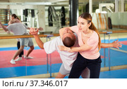 Young woman practicing inverted facelock on male opponent in gym. Стоковое фото, фотограф Яков Филимонов / Фотобанк Лори