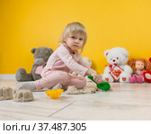 Двухлетняя девоччка играет с кинетическим песком на полу в детской комнате. Стоковое фото, фотограф Наталья Гармашева / Фотобанк Лори