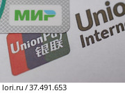Пластиковая карта платежной системы "Мир" на фоне логотипа UnionPay крупным планом (2022 год). Редакционное фото, фотограф Гребенев Пётр / Фотобанк Лори