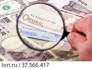 Лупа в руке фокусируется на банкнотах евро в окружении различных валют. Стоковое фото, фотограф Александр Гаценко / Фотобанк Лори