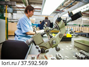 Stepnogorsk, Kazakhstan April 04, 2012: Bearing production plant. Vintage Soviet measuring instrument micrometer and bearing rollers in the foreground. Woman worker is blurred on the background. Редакционное фото, фотограф Alexey Rezvykh / Фотобанк Лори