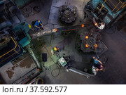 Stepnogorsk, Kazakhstan April 04, 2012: Bearing production plant workshop. Production red-hot outer-race bearing parts on conveyor. Operator workers and equipment. Редакционное фото, фотограф Alexey Rezvykh / Фотобанк Лори