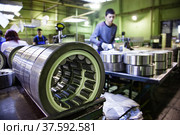 Stepnogorsk, Kazakhstan April 04, 2012: Bearing production plant. Ready roll bearings on quality control line. Low depth of field, young worker out of focus. Редакционное фото, фотограф Alexey Rezvykh / Фотобанк Лори