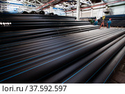 Stepnogorsk, Kazakhstan - April 04, 2012: Plastic pipes production plant warehouse. Workers with crane hook. Редакционное фото, фотограф Alexey Rezvykh / Фотобанк Лори