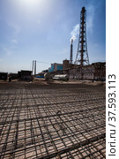 Factory chimney (smoking stack) and steel reinforcement building basement. Phosphoric fertilizers plant modernization. Blue sky and sun. Стоковое фото, фотограф Alexey Rezvykh / Фотобанк Лори