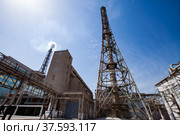 Plant chimney (smoking stack) and pipelines of phosphoric fertilizers plant on blue sky with sun background. Chemical industry. Стоковое фото, фотограф Alexey Rezvykh / Фотобанк Лори