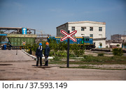 Taraz/Kazakhstan: Phosphoric fertilizers plant. Two workers waiting train. Blue locomotive and green railway carriage on industrial buildings and pipeline background. Стоковое фото, фотограф Alexey Rezvykh / Фотобанк Лори